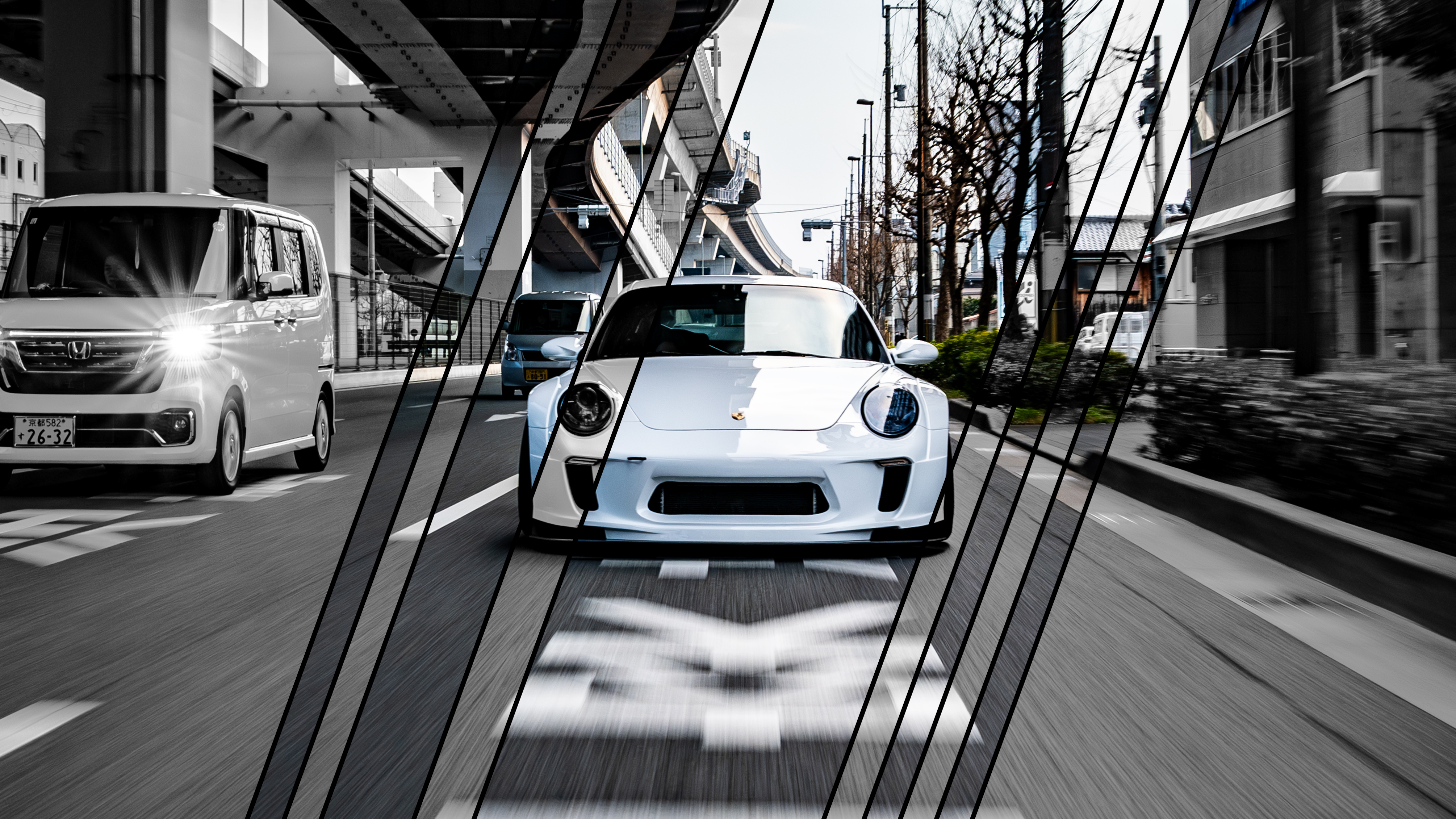 White Pandem widebody Porsche 911 head-on under a Tokyo highway underpass